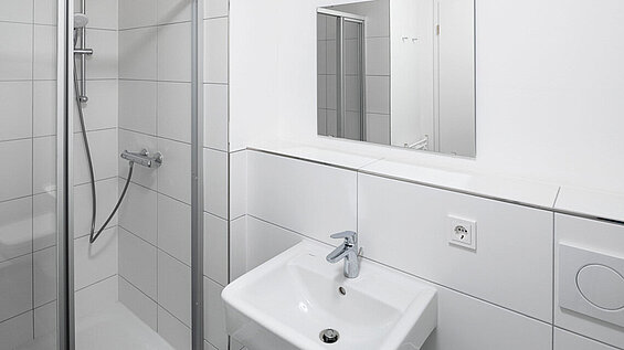 Ansicht des Badezimmers mit Duschkabine, Spiegel, Toilette und Waschbecken 